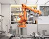 Ein Roboterarm transportiert Kunststoffabschlussscheiben